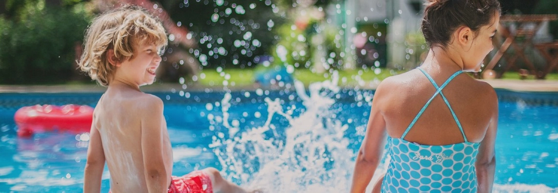 Zwei Kinder planschen fröhlich im Swimmingpool.